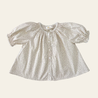 Elma Delphi Blouse in Haru Blossom Iris, featuring delicate purple florals on white Japanese-milled cotton, a shirred neckline, puff sleeves with elasticated cuffs and picot lace trim.