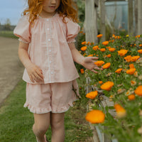 Elma Lilia Shorts in pink and white Sweet Pea Gingham, featuring an elasticated drawstring waistband, side pockets and ruffled hems with delicate white picot lace trim.