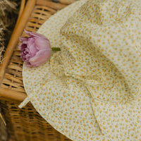 Elma Poppy Sunhat in Haru Blossom Buttercup, featuring tiny tonal blossoms on soft buttery-yellow Japanese cotton, an adjustable crown tie and under-chin tie with toggle.