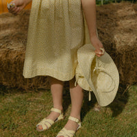 Elma Colette Dress in Japanese Floral, featuring tiny yellow flowers on a soft buttery-yellow cotton base, Peter Pan collar and gathered skirt.