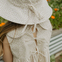 Elma Poppy Sunhat in Haru Blossom Iris, featuring tiny purple blossoms scattered across soft white Japanese-milled cotton, an adjustable crown tie and under-chin tie with toggle.