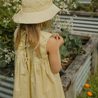 Elma Colette Dress in Japanese Floral, featuring tiny yellow flowers on a soft buttery-yellow cotton base, Peter Pan collar and gathered skirt.