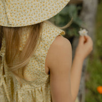 Elma Colette Dress in Japanese Floral, featuring tiny yellow flowers on a soft buttery-yellow cotton base, Peter Pan collar and gathered skirt.