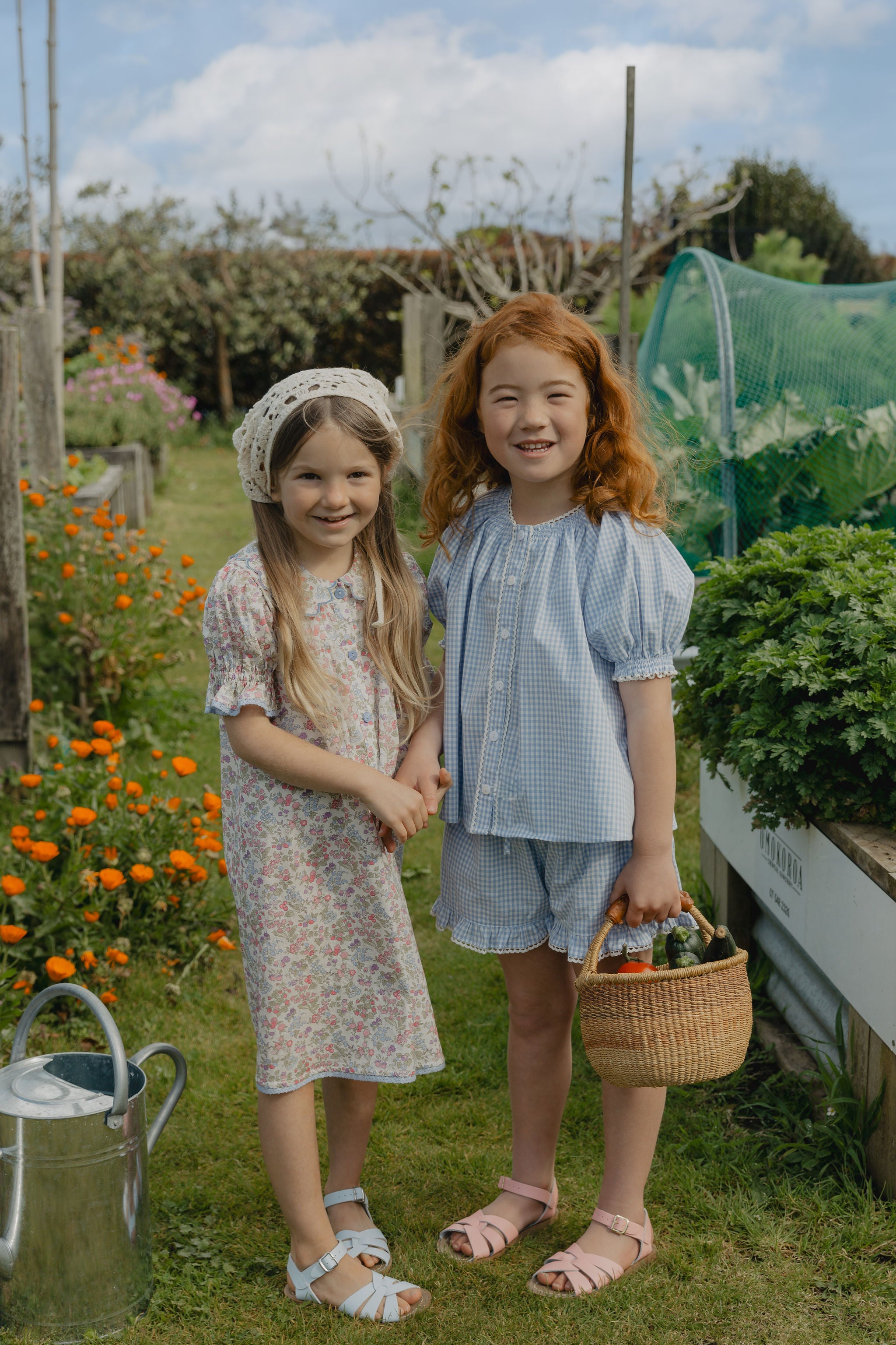 Elma Lilia Shorts in blue and white Cottage Blue Gingham, featuring an elasticated drawstring waistband, side pockets and ruffled hems with delicate white picot lace trim.