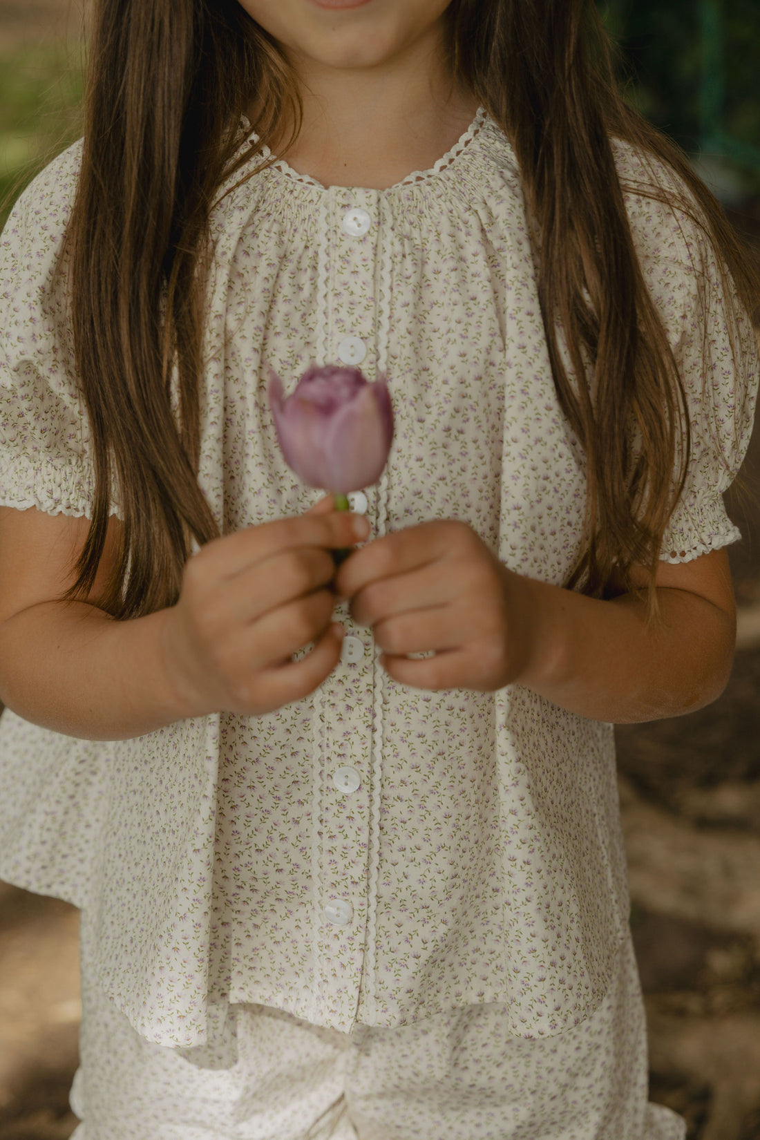 Elma Delphi Blouse in Haru Blossom Iris, featuring delicate purple florals on white Japanese-milled cotton, a shirred neckline, puff sleeves with elasticated cuffs and picot lace trim.
