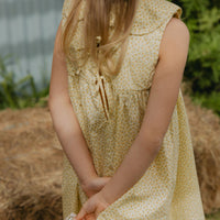 Elma Colette Dress in Japanese Floral, featuring tiny yellow flowers on a soft buttery-yellow cotton base, Peter Pan collar and gathered skirt.