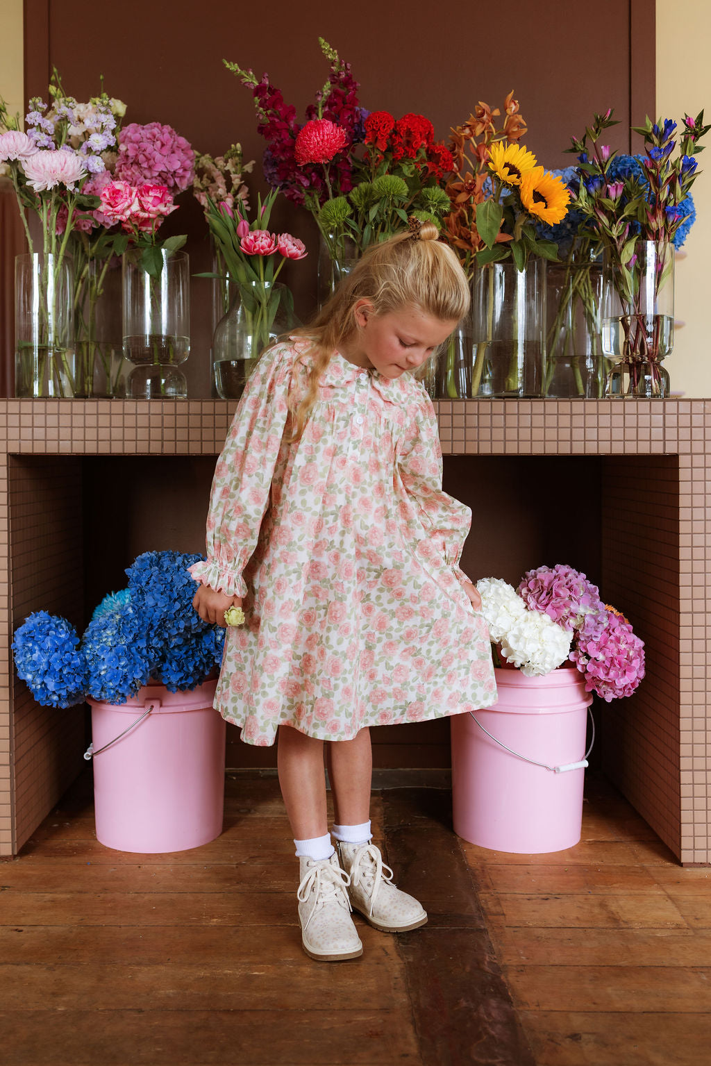 Girl wearing the Elodie Dress in Liberty Willmotts Roses floral print in pink and cream tones, with scalloped Peter Pan collar puff long sleeves.