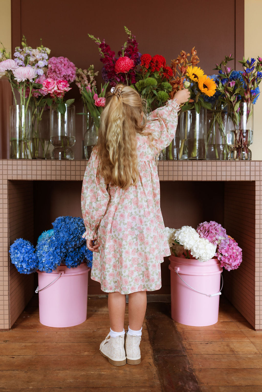 Girl wearing the Elodie Dress in Liberty Willmotts Roses floral print in pink and cream tones, with scalloped Peter Pan collar puff long sleeves.