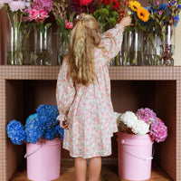 Girl wearing the Elodie Dress in Liberty Willmotts Roses floral print in pink and cream tones, with scalloped Peter Pan collar puff long sleeves.