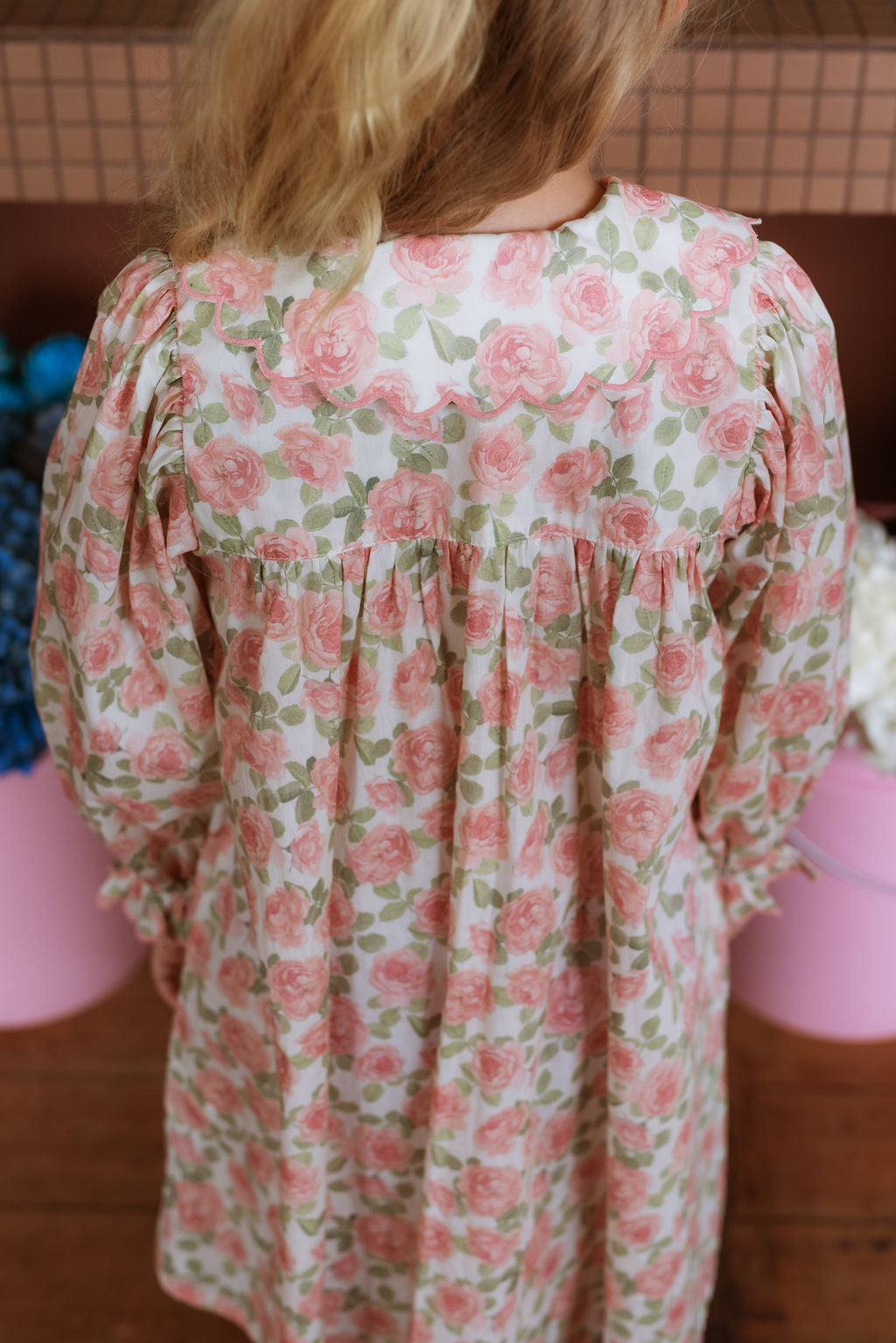 Girl wearing the Elodie Dress in Liberty Willmotts Roses floral print in pink and cream tones, with scalloped Peter Pan collar puff long sleeves.