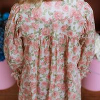 Girl wearing the Elodie Dress in Liberty Willmotts Roses floral print in pink and cream tones, with scalloped Peter Pan collar puff long sleeves.