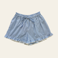 Elma Lilia Shorts in blue and white Cottage Blue Gingham, featuring an elasticated drawstring waistband, side pockets and ruffled hems with delicate white picot lace trim.