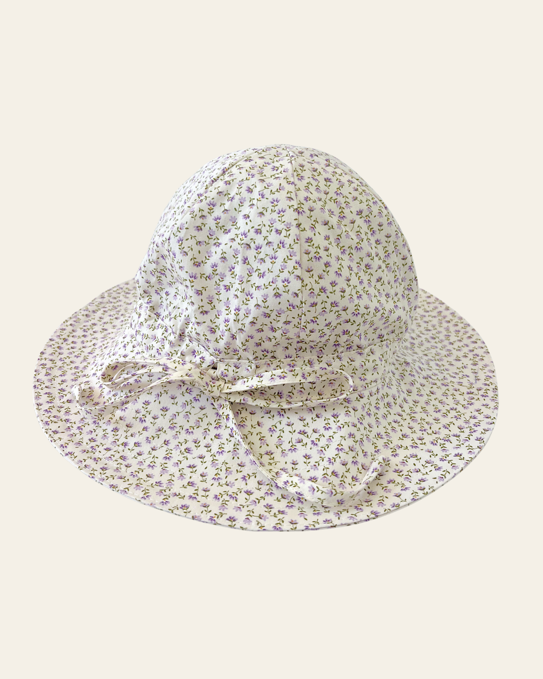 Elma Poppy Sunhat in Haru Blossom Iris, featuring tiny purple blossoms scattered across soft white Japanese-milled cotton, an adjustable crown tie and under-chin tie with toggle.