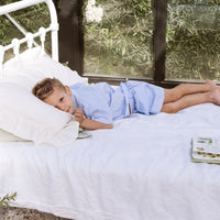 Little boy lying on a bed wearing a blue stripe shirt and shorts set.